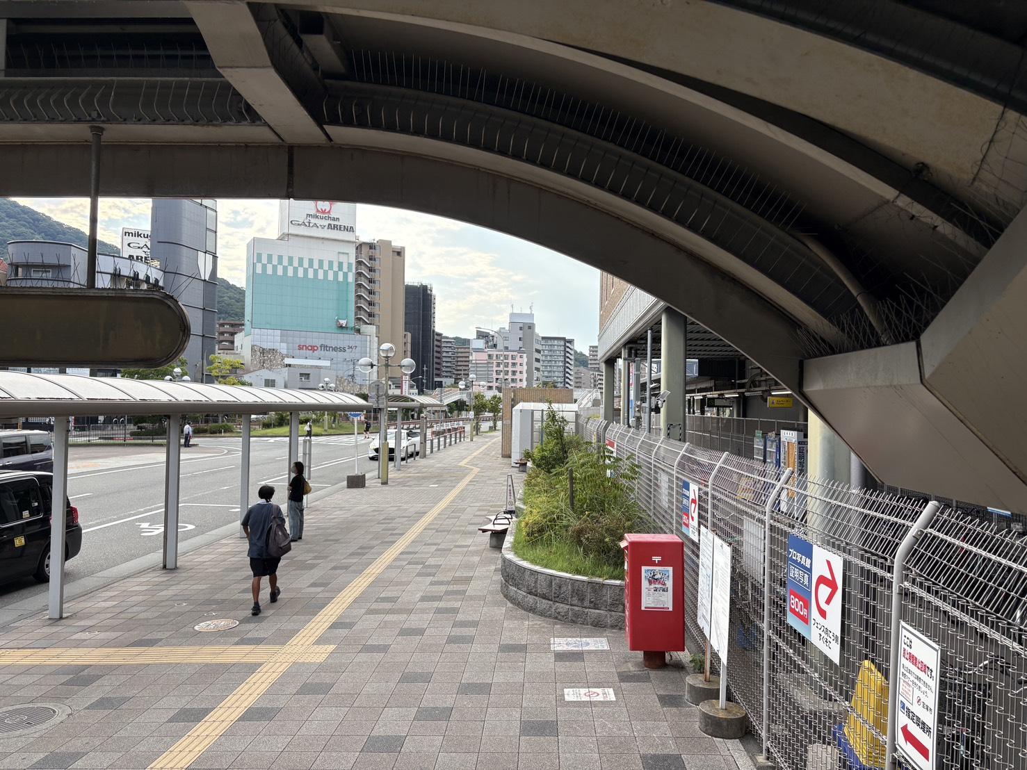 高架下から見える歩道の先のピンクの建物